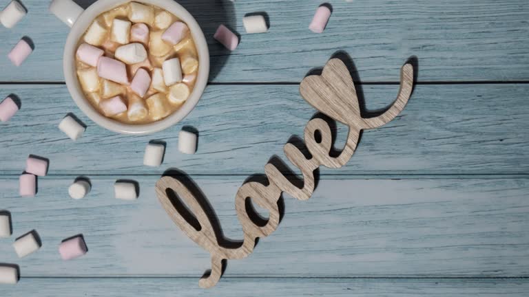 Zoom in out Wooden word love with heart romance with white coffee cup of hot chocolate and small marshmallows. Minimal concept of greeting card for Valentine's Day, Mother's Day, Women's Day Festive holiday card concept