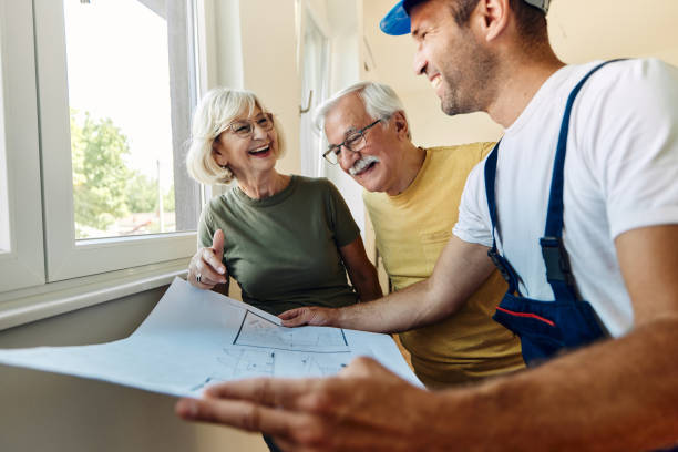 istock Happy senior couple analyzing housing plans with manual worker. 1487730763