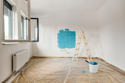 Blue paint on the wall and ladders during home renovation process in the apartment. Copy space.