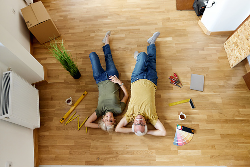 High angle view of happy mature couple lying on the floor during a break from renovating their new apartment. Copy space.