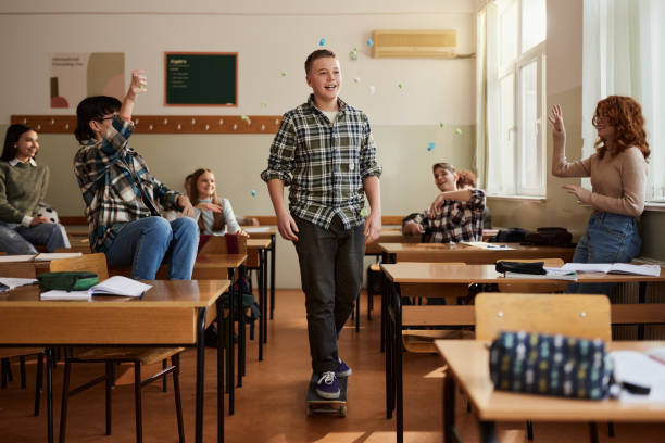 Students throwing papers on their friend who is skateboarding at school.