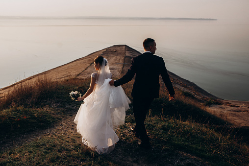 bride and groom walk on the pier. wedding photoset. sea wedding. newlyweds pose by the seashore. honeymoon by the sea