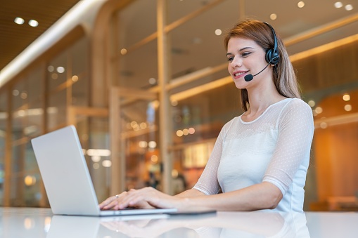 Half length mid shot of multiracial customer support woman working out of home, from a workspace shared office cafe.