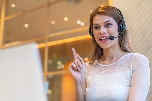 Close up mid shot of multiracial customer support woman working out of home, from a workspace shared office cafe.