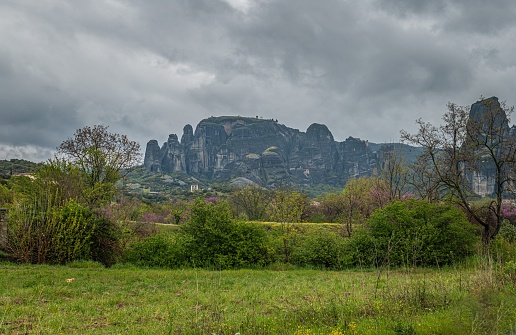 A green meadow with a scenic mountain range in the background. Meteora, Kalabaka, Greece.