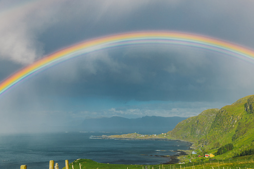 Rainbow over stormy sky. Rural landscape with rainbow over dark stormy sky in a countryside at summer day.