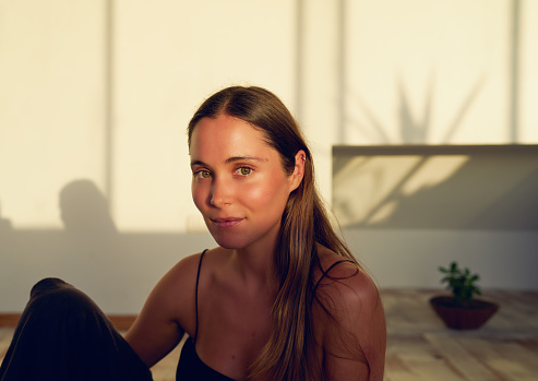 head portrait beautiful young caucasian woman sitting in yoga studio in sunset light