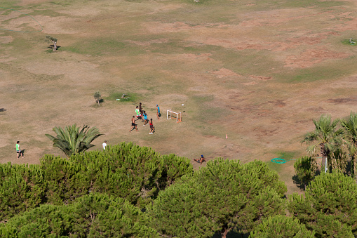 Rome, Italy - 24 NOVEMBER 2022: local young people playing football in the playground next to a modern township; for lucky and talented players, soccer is a fast way to escape poverty of slums photo