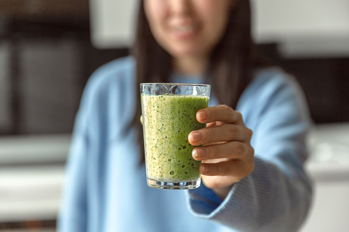Girl showing a glass of green smoothie