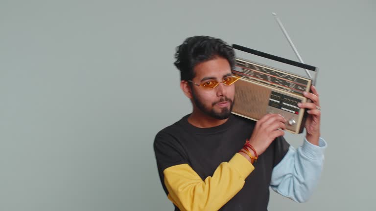 Indian man using retro tape record player to listen music disco dancing of favorite track having fun