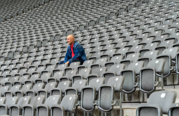 niedrige winkelansicht des mannes, der im stadion sitzt - bleachers stadium empty seat stock-fotos und bilder