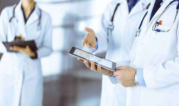 istock Group of unknown doctors use a computer tablet to check up some medical names records, while standing in a hospital office. Physicians ready to examine and help patients 1487763533