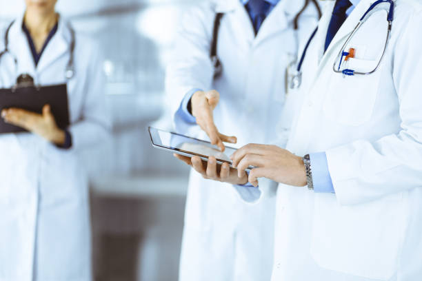 istock Group of unknown doctors use a computer tablet to check up some medical names records, while standing in a hospital office. Physicians ready to examine and help patients 1487763540