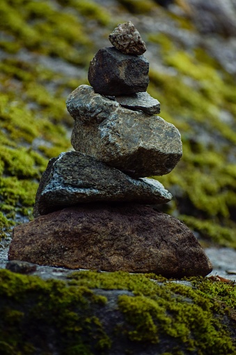 A vertical shot of stacked rocks on a lush green mossy surface