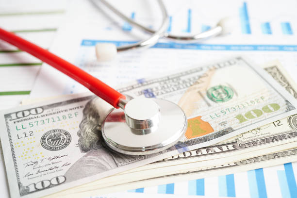 istock Stethoscope and US dollar banknotes on chart or graph paper, Financial, account, statistics and business data  medical health concept. 1487768417