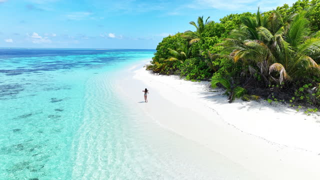Aerial view of woman walking on incredible Maldivian beach