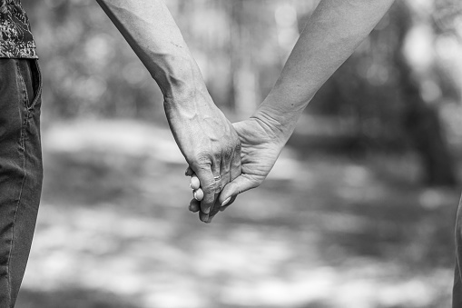 The husband's hand firmly holds the wife's hand close-up. Loving couple walking and holding hands. Reliable and strong marriage. The concept of romance, fidelity in marriage and love. Black and white