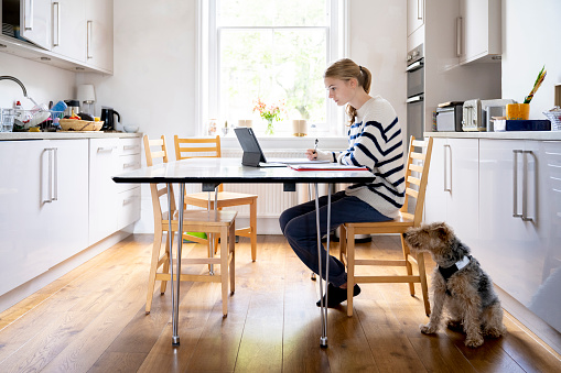 15 year old blond haired white female sitting doing homework at kitchen table studying for her exams