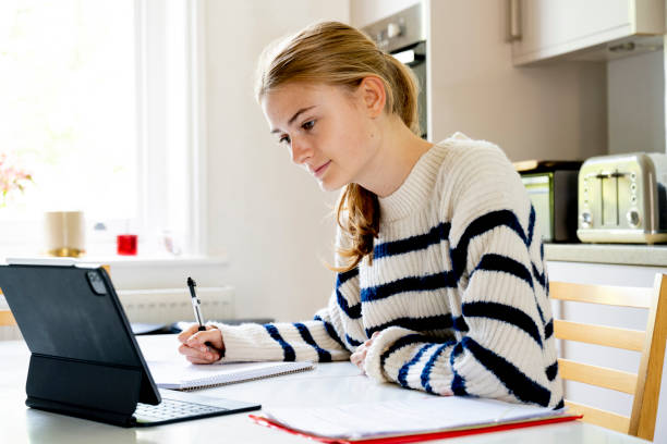 istock 15 year old girl sitting in kitchen doing homework 1487781129