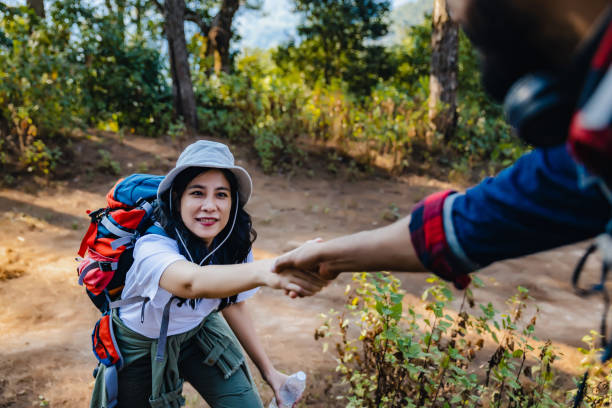 istock Woman hike  being pulled up by helping hand. Hiker friends help each other up a mountain. Man and woman giving a helping hand and active fit lifestyle. Hikers with backpacks helping  friend to climb 1487783701