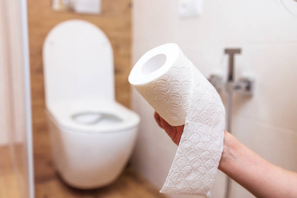 la mano della donna strappa il rotolo di carta igienica bianca da vicino. sfondo del bagno - bidet foto e immagini stock