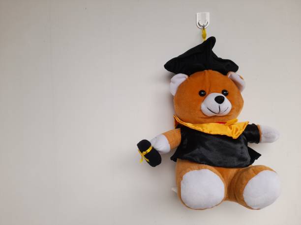 istock cute graduation doll front view against white wall background. 1487785633