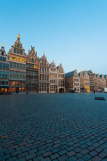 The historic guild houses of Antwerp stand in the large Grote Markt plaza in the evening blue hour in Antwerp, Belgium