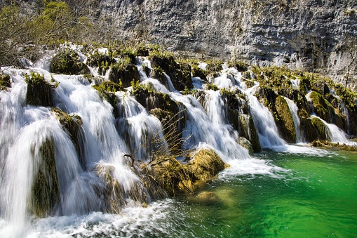 A scenic view of rushing Plitvice lakes cascading down a rocky mountain, Croatia