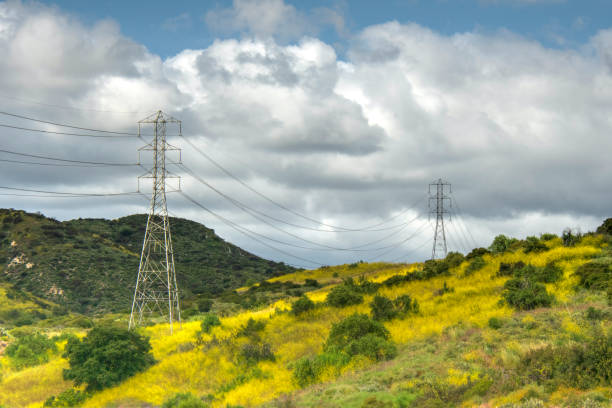 Electrical towers atop hills with cloudy sky