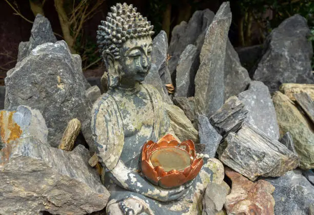 Photo of Buddha statue sits in a rock garden