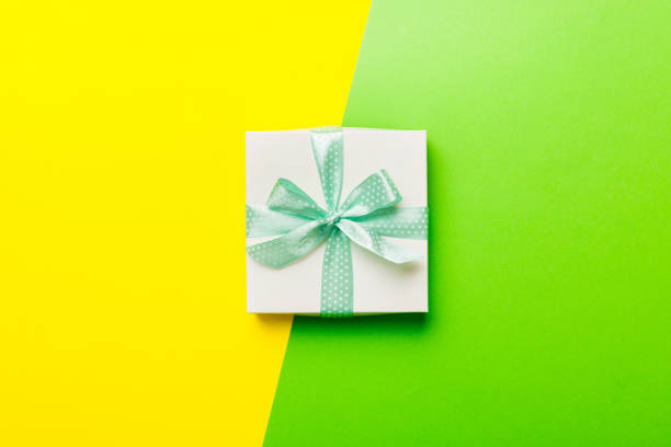 holiday handmade white present tied green ribbon bow top view with copy space. Flat lay holiday background. Birthday or christmas present. Christmas gift box concept with copy space.