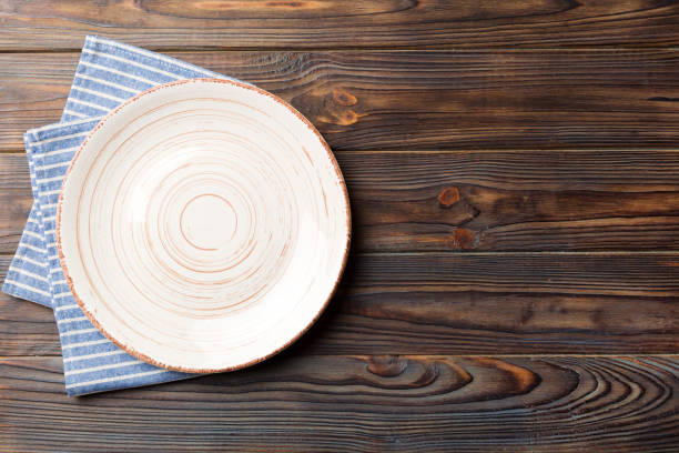 istock Top view on colored background empty round white plate on tablecloth for food. Empty dish on napkin with space for your design 1487797886