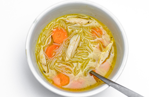 Fatty chicken soup in a white bowl on a white background