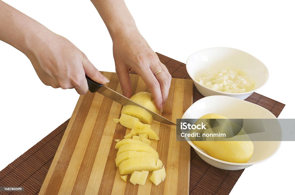 Preparing meal ingredients Beautiful women's hands cutting potato cubes, isolated on a white background. Potato and onion meal ingredients prepared for cooking. Brown Stock Photo