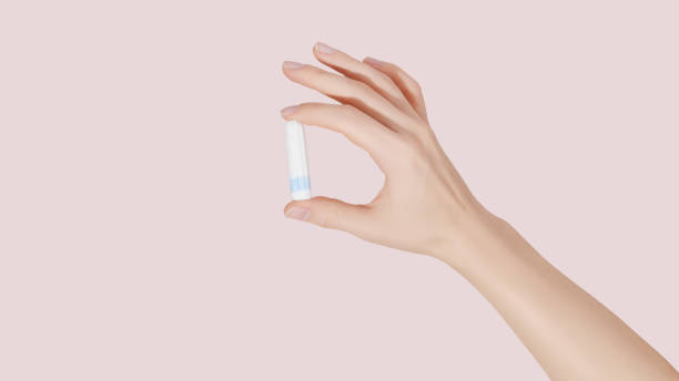 istock Woman's hand holding a clean cotton tampon on pink background. 1487803748