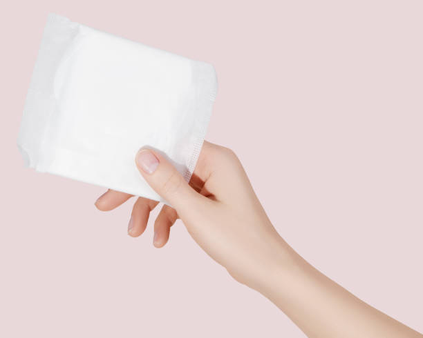 Female hand holding a sanitary pad for menstruation. Concept: female's hygienic product for period's day. Woman healthcare. Monthly intimate hygiene. stock photo
