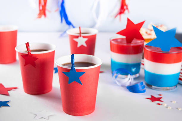 Independence Day Fourth of July USA American patriotic party with american symbols. Paper cup with drinks and tasty dessert layered colorful jelly with stars on the background stock photo