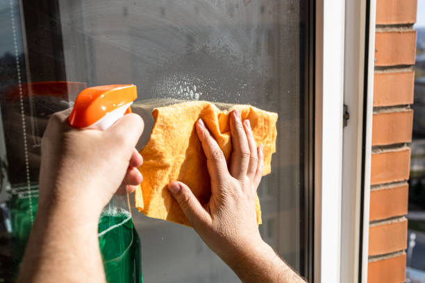 cleaning outdoor window glass with spray and rag stock photo