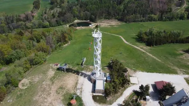 Aerial shot of a large communication tower in a vast rural landscape with a small residential building in the foreground
