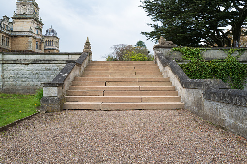 Grand stone outside staircase seen at a former stately home, now a luxury hotel. Part of the hotel can be seen.