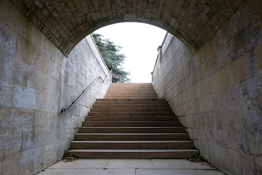 An underground tunnel leading to a wide stairway at a once English stately home, now a luxury hotel. Wooden stocks can be seen at the top.