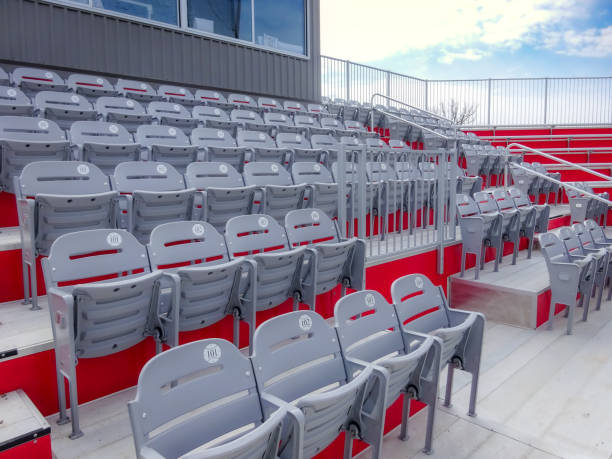 istock Rows of empty gray seats in a stadium with silver number tags shaped like baseballs or softballs. 1487811832