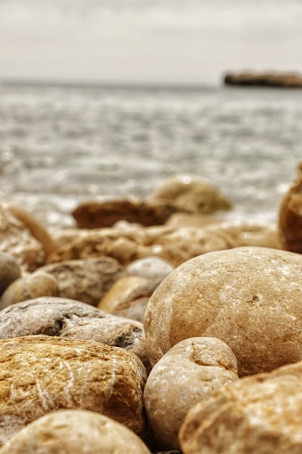 A vibrant image of a rocky beach shoreline, taken from a vertical angle