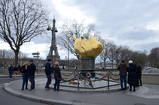 Paris, France - March 19, 2023: The Flame of Liberty, a gold leaf covered replica of the flame from the Statue of Liberty and the Eiffel Tower at the background in Paris, France.
