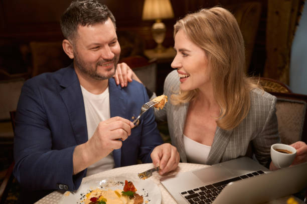 istock Man in love feeding his girlfriend in cozy restaurant 1487815736