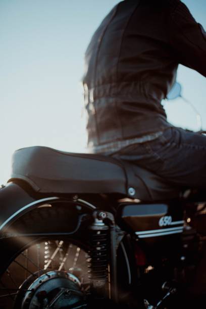 istock Man wearing a leather jacket and riding a motorcycle on a sunny day against a serene blue sky 1487816979