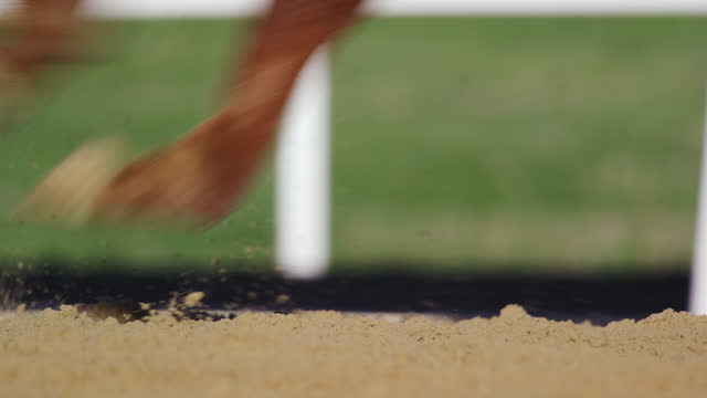 Slow Motion, Close-Up Shot of Dirt Being Kicked Up by a Thoroughbred Racehorse's Feet at a Racetrack on a Sunny Day