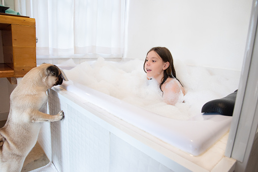 child in bathtub with foam playing with pet outside