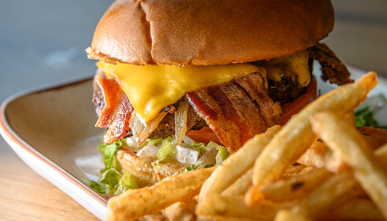 A cheeseburger with all of the toppings, served with a side of seasoned french fries.