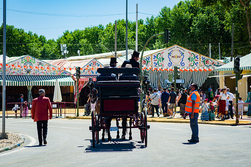 Seville, Spain - April 26, 2023: traffic officer shows a horse-drawn carriage access to the real de la feria de sevilla